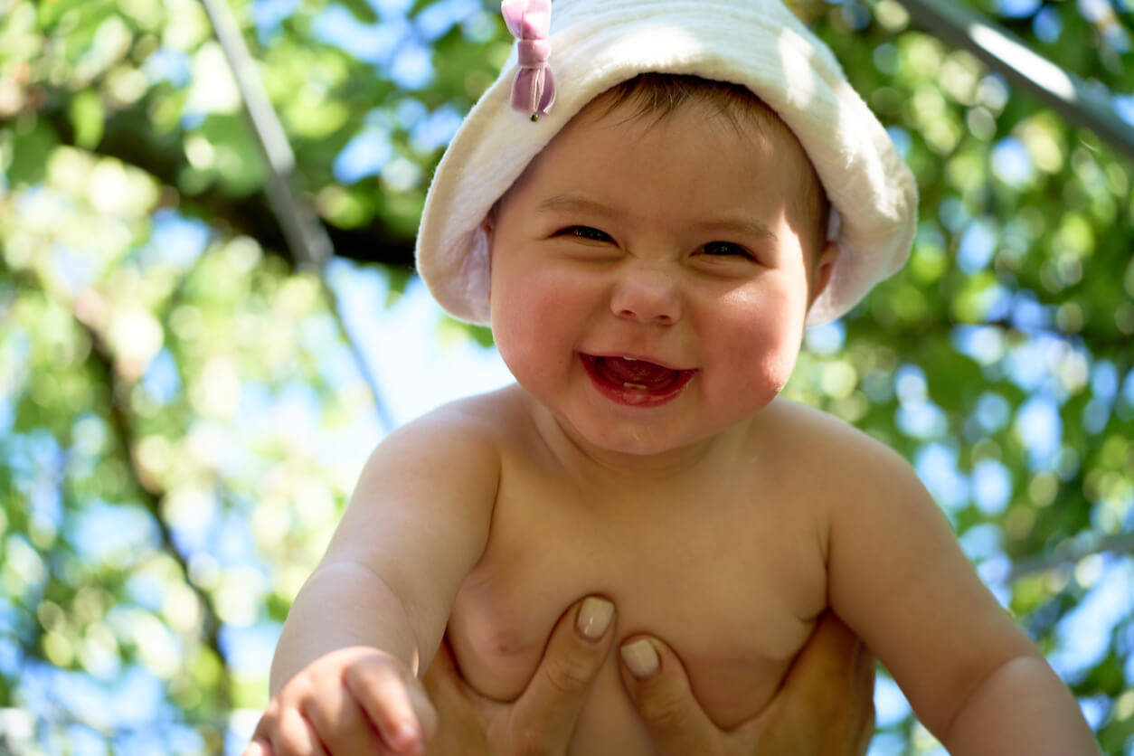 En baby som ler mens den holdes i luften.