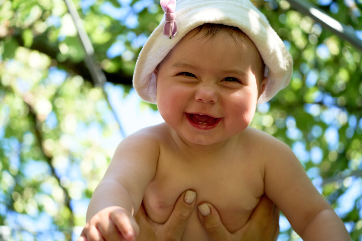 A baby laughing while being held in the air.