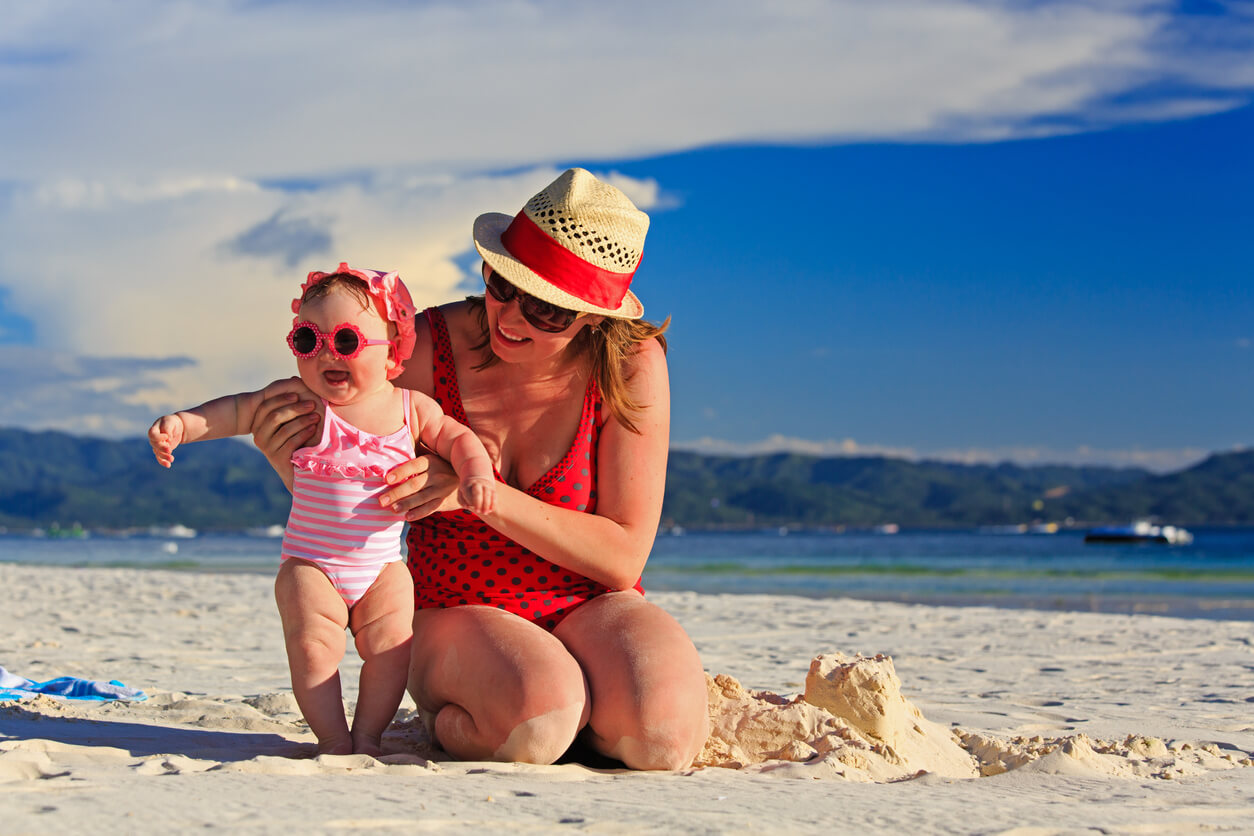 A mother playing with her baby at the beach.