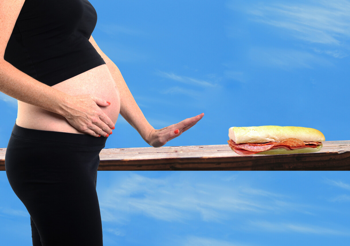 Une femme enceinte qui dit non à un sandwich au bacon.