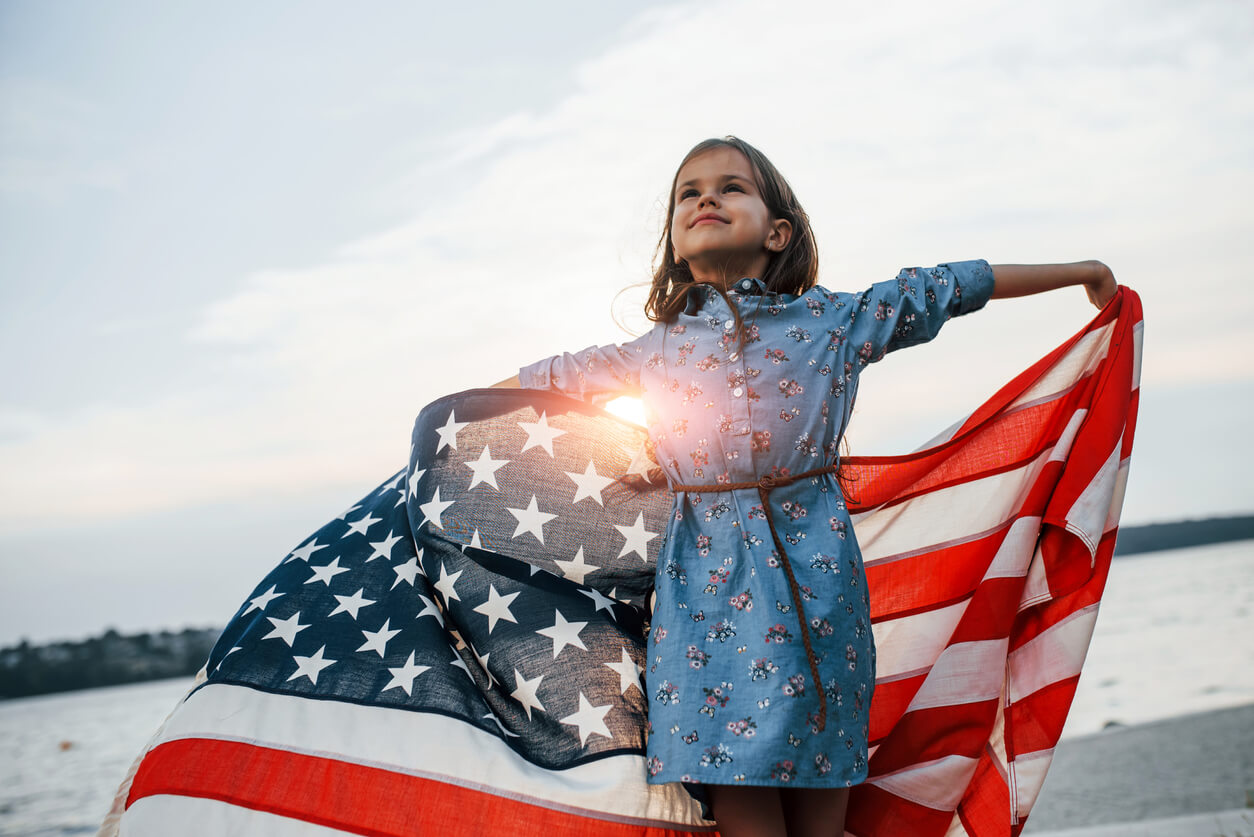 A young girl holding the American flag.