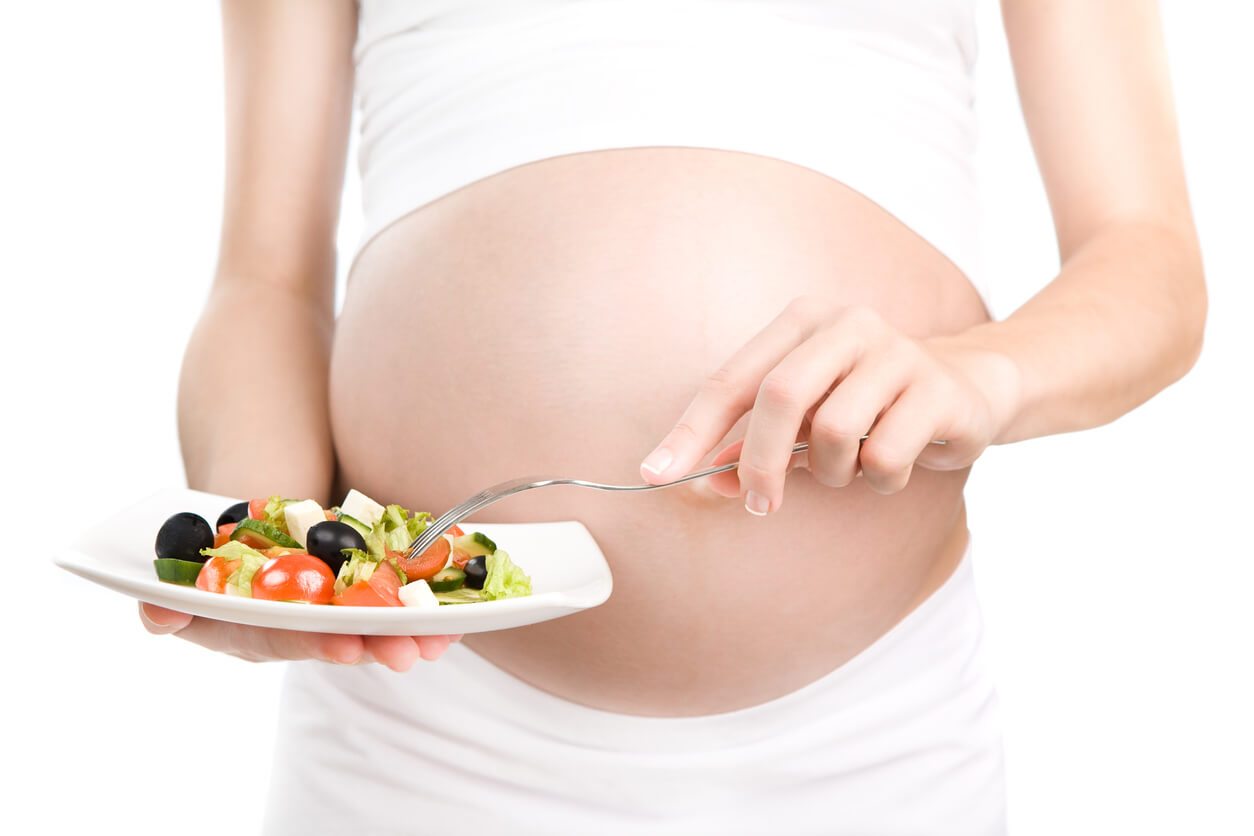 Mujer embarazada comiendo ensalada.