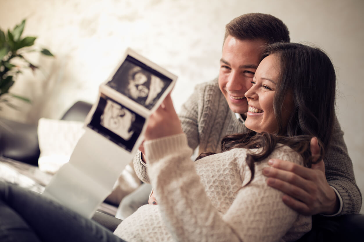 Geburtshilflicher Ultraschall - werdende Eltern betrachten Ultraschallbilder ihres Babys