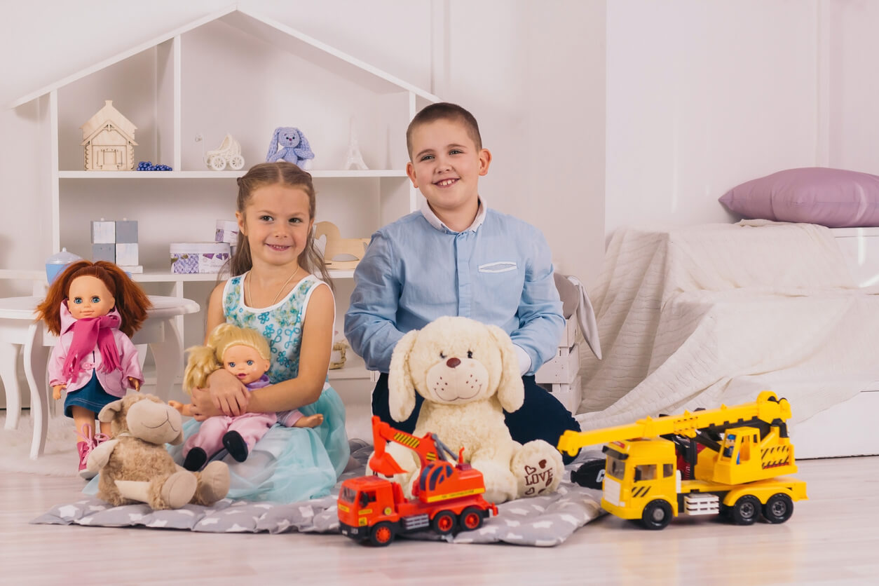 Une fille avec une poupée et un garçon avec des voitures.