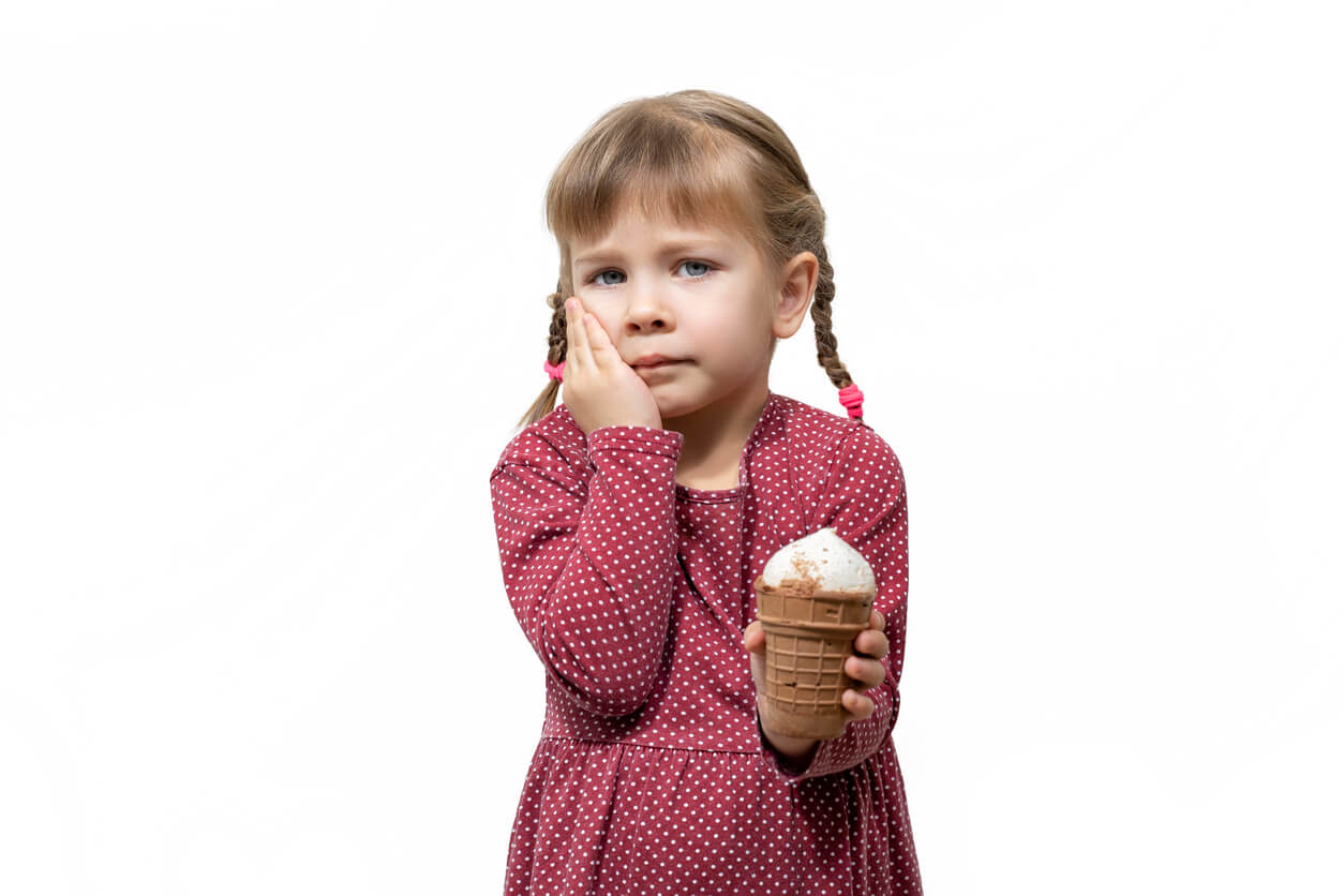 Une jeune fille qui a mal aux dents et ne peut pas manger une glace.