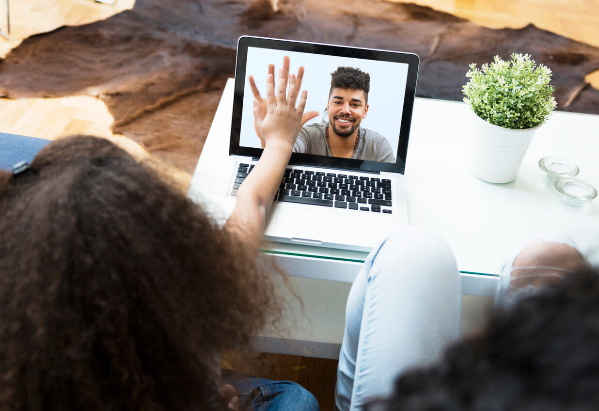 Et barn high-fiving faren sin via en videosamtale.