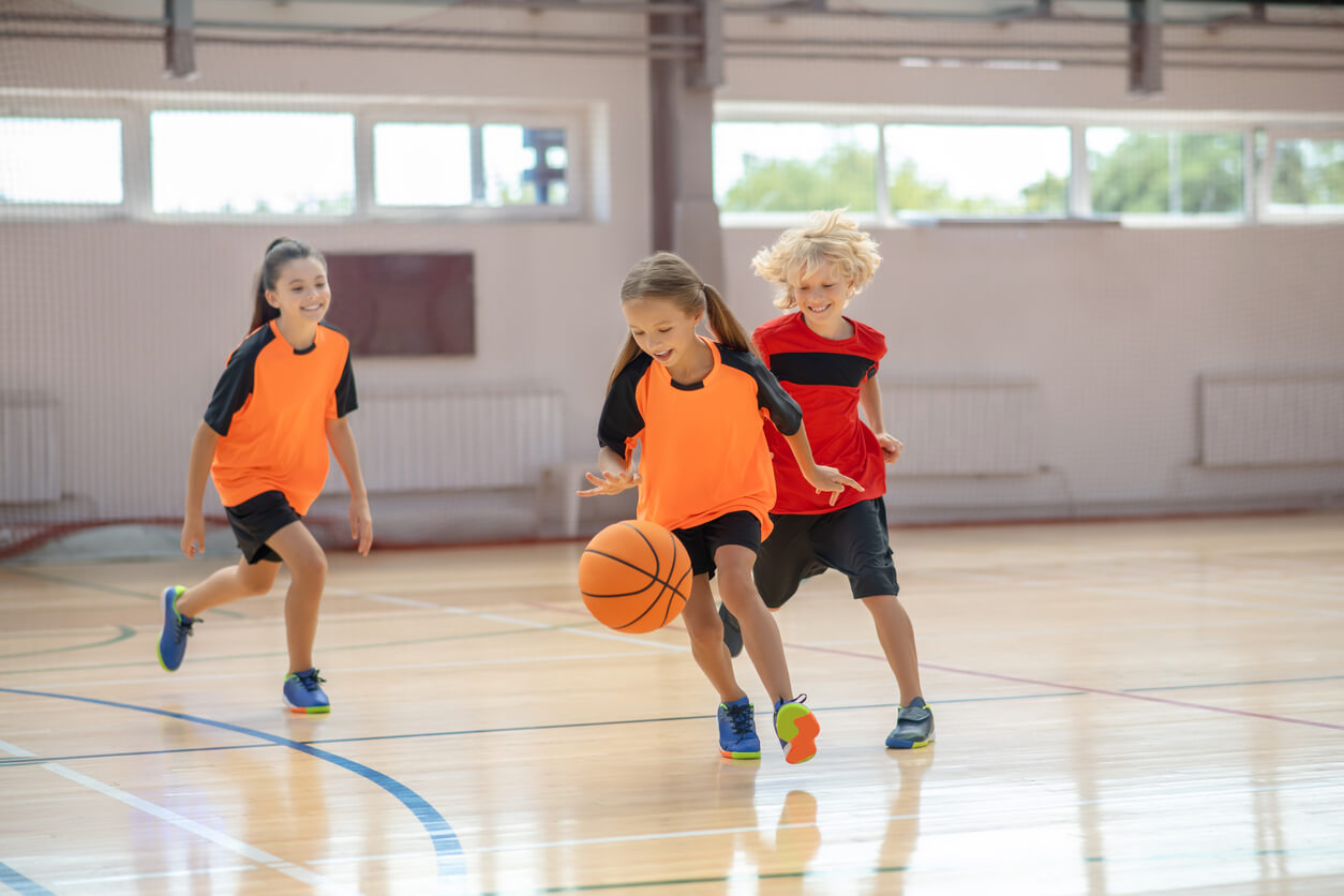 Trois enfants qui jouent au basket.