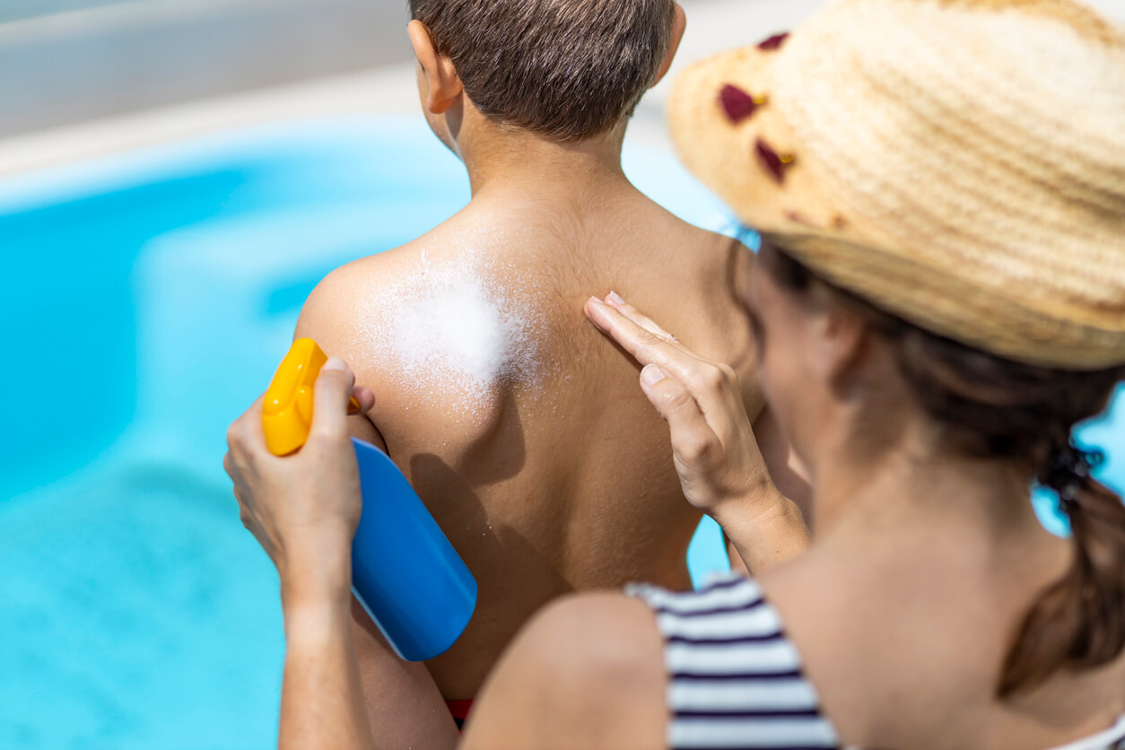 A mother putting sunscreen on her son's back.