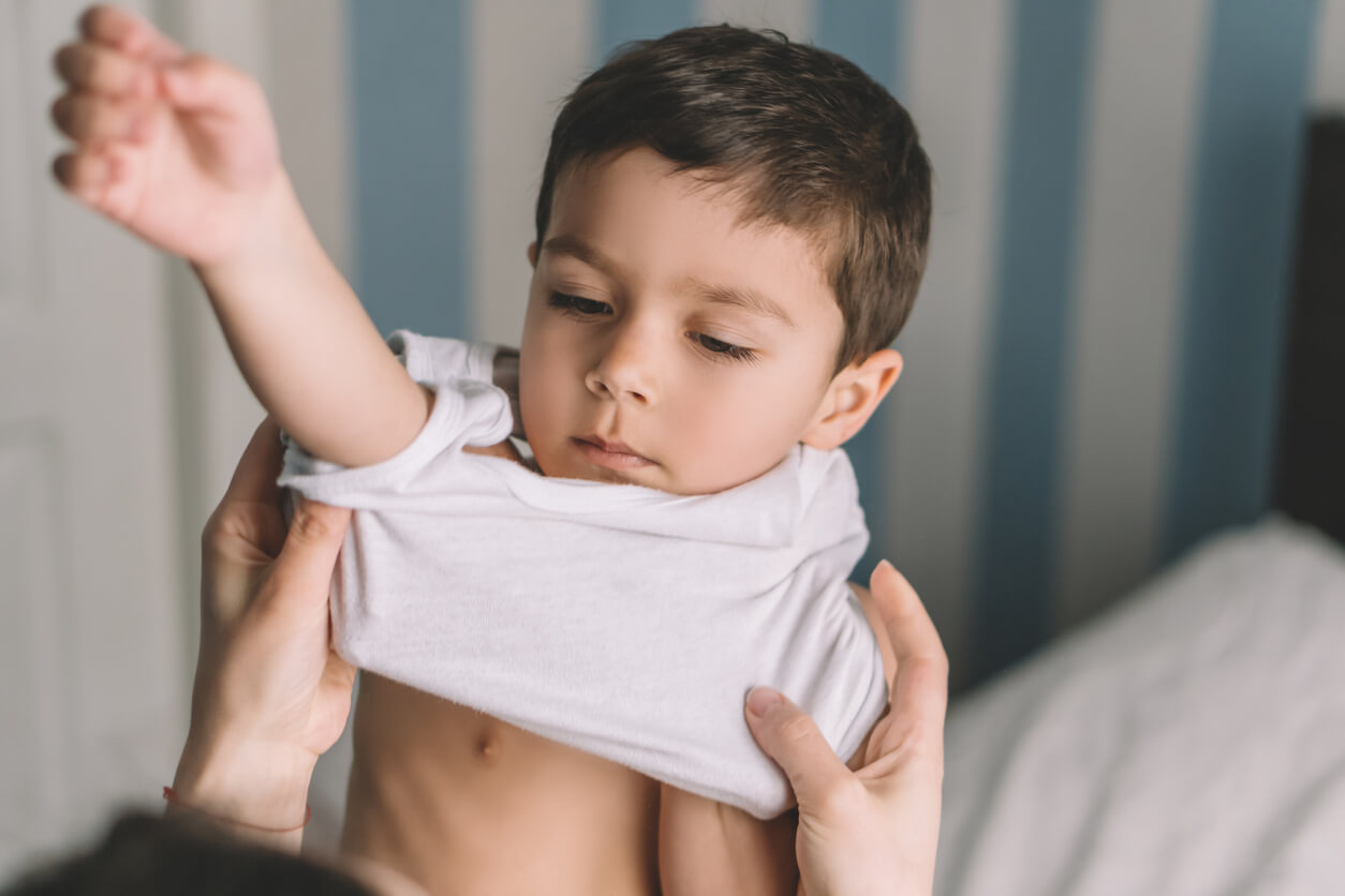 Un enfant qui s'habille avec l'aide d'un adulte.
