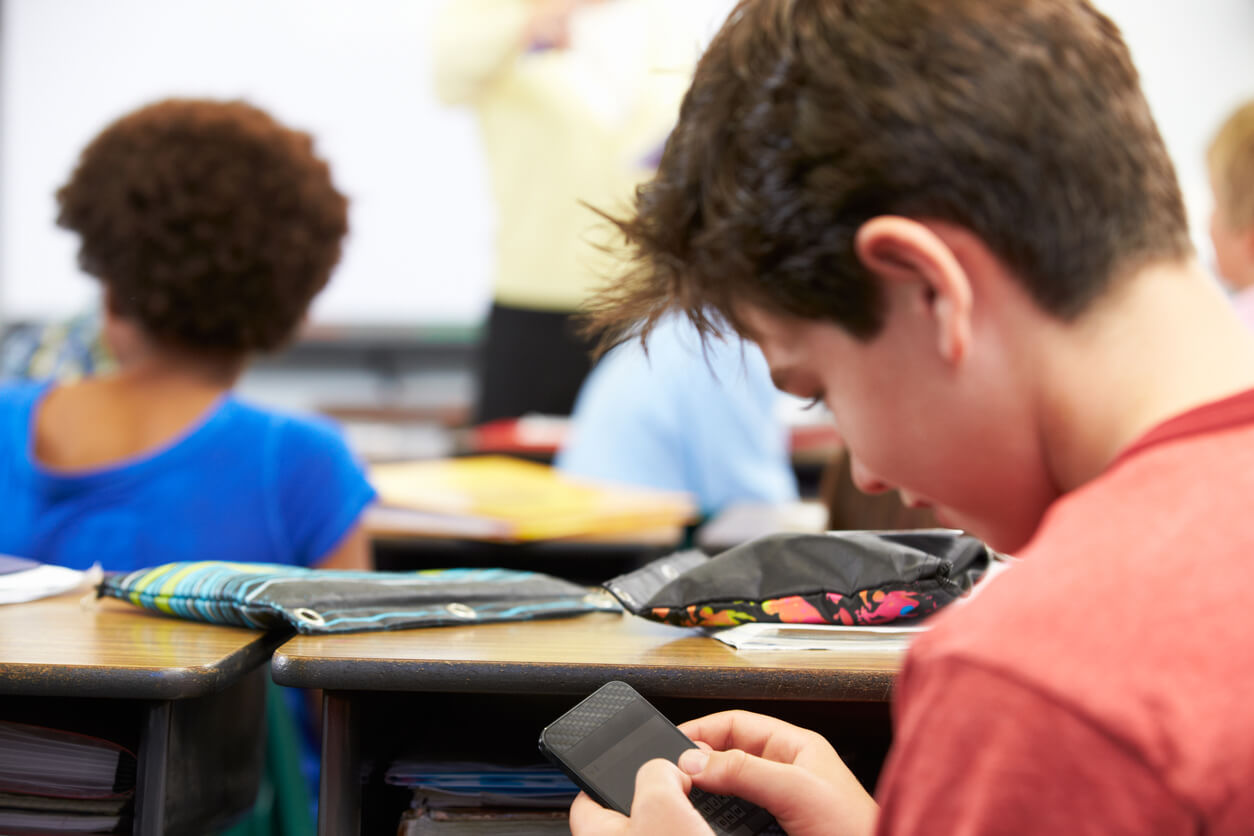Un adolescent sur son téléphone en classe.