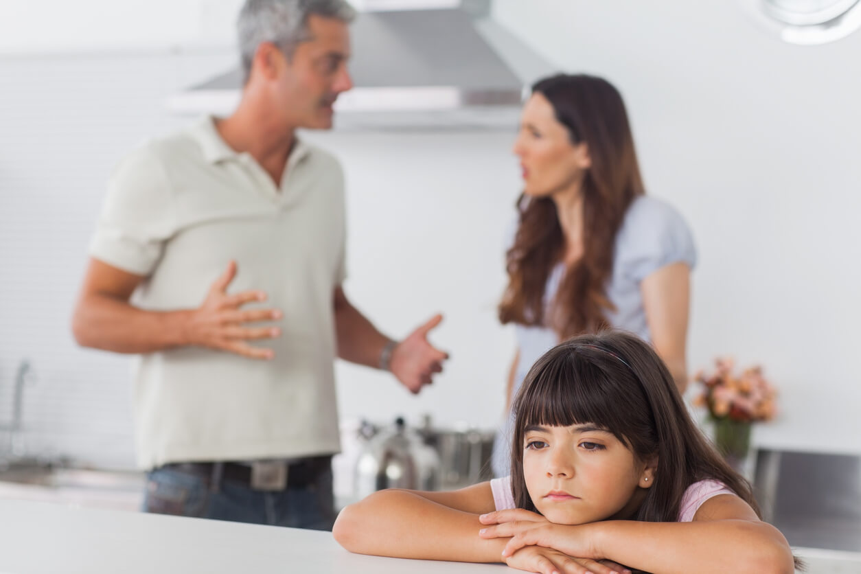 Parents arguing in front of their daughter, who looks sad.