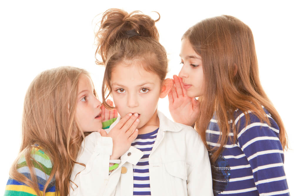 Trois jeunes filles qui se parlent dans l'oreille.