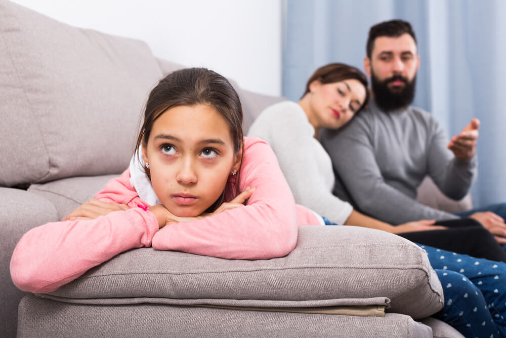 Deux parents sur un canapé avec leur fille qui leur tourne le dos. 