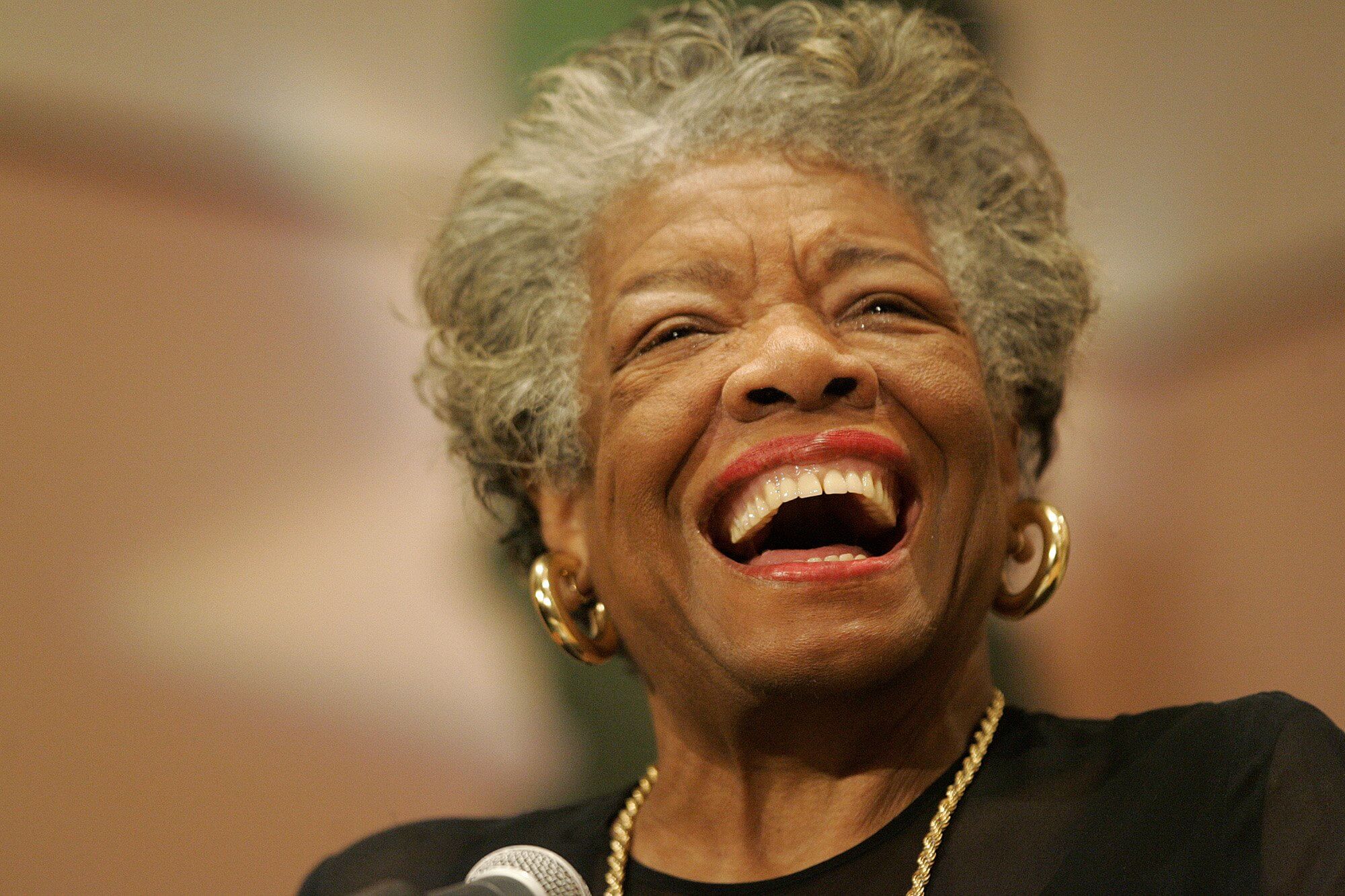 A photo of Maya Angelou laughing during a speech.