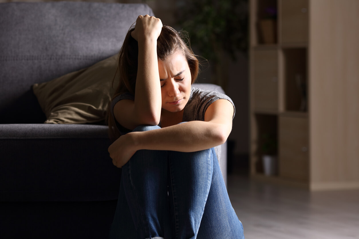 A teenage girl sitting on the floor looking overwhelmed.