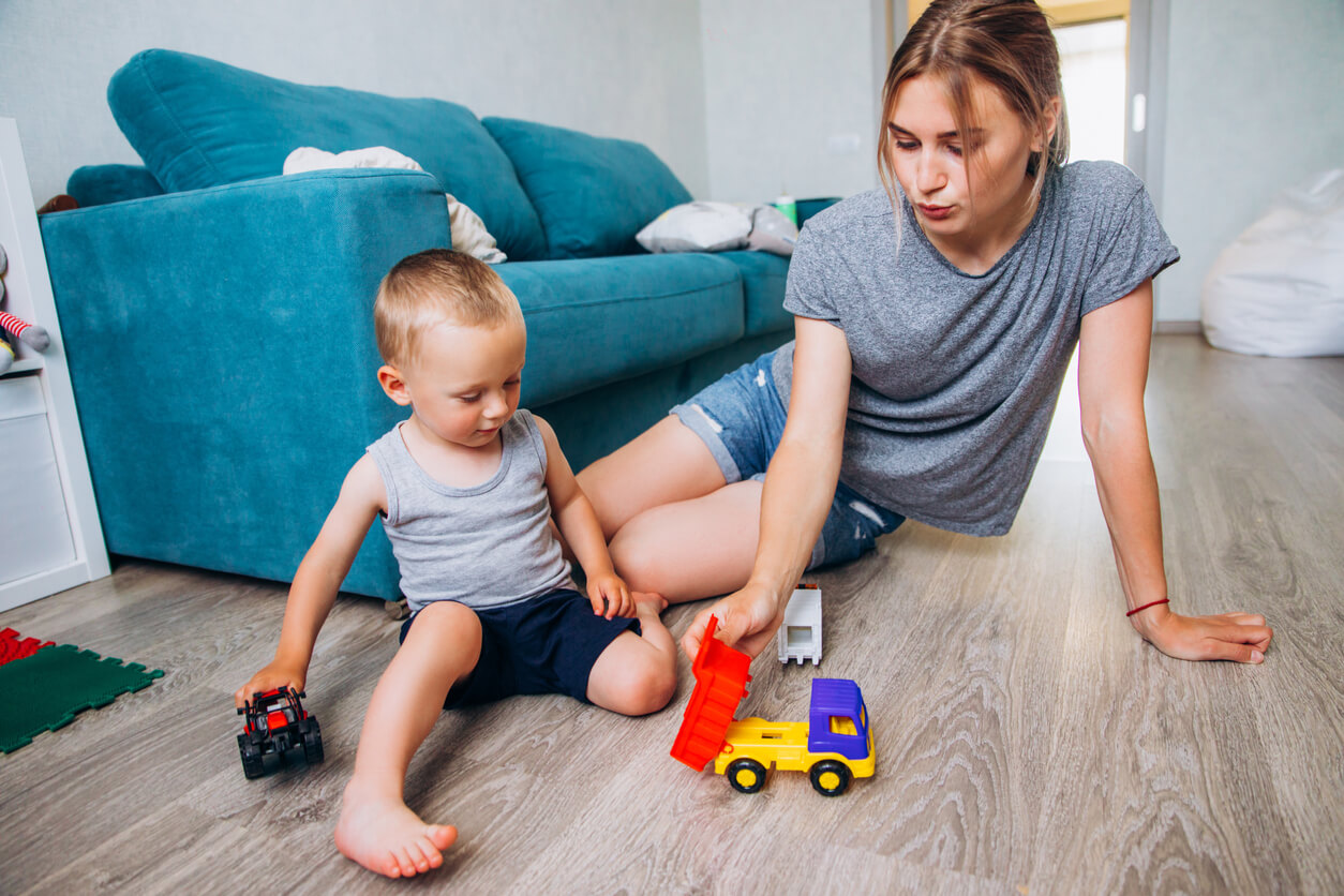 A mother and her baby boy playing with toy trucks.