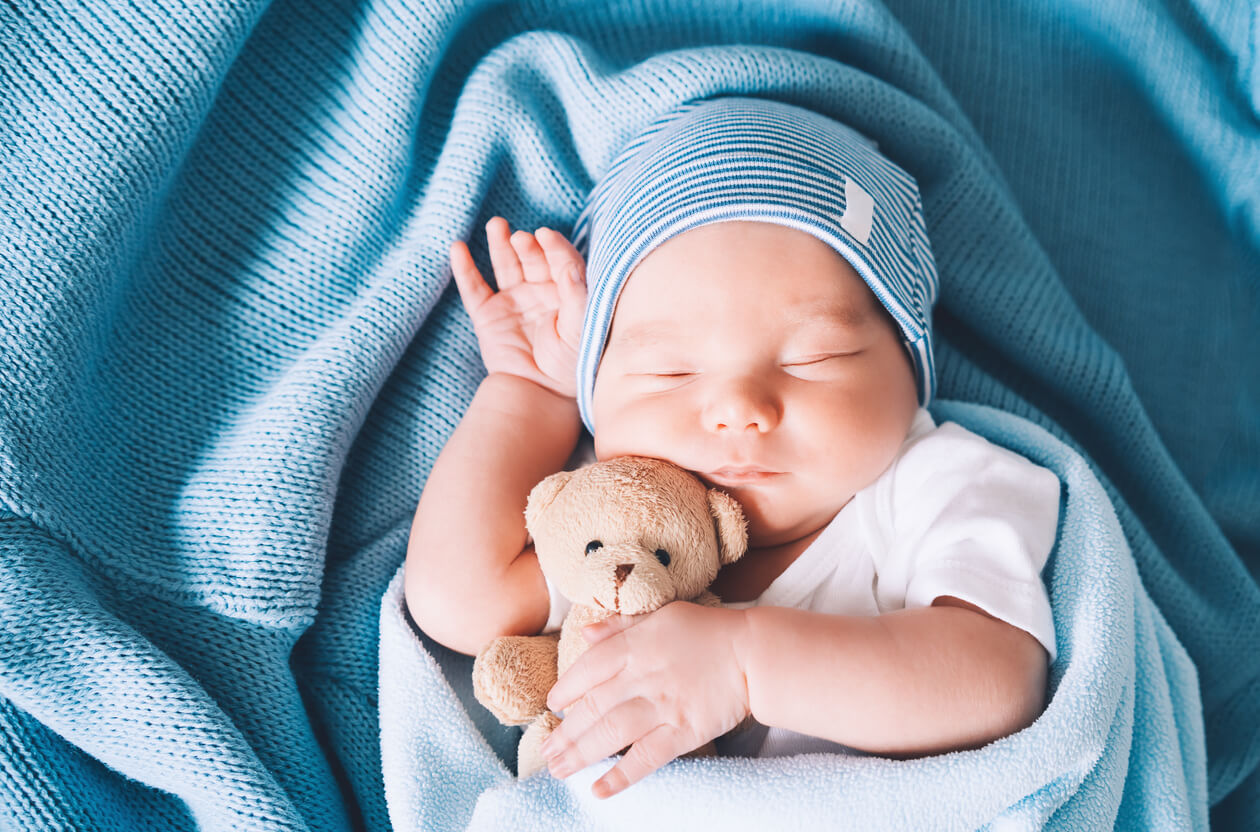 A baby sleeping with a teddy bear.