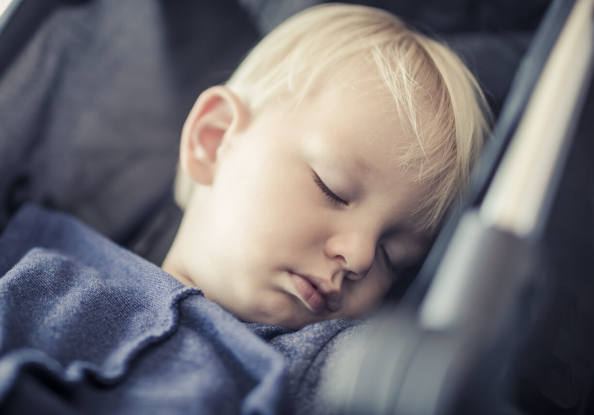 A toddler sleeping in a carseat.