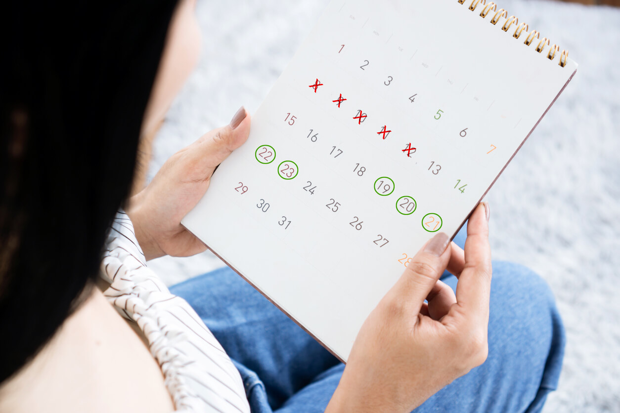 A woman looking at a calendar to track her menstrual cycle.