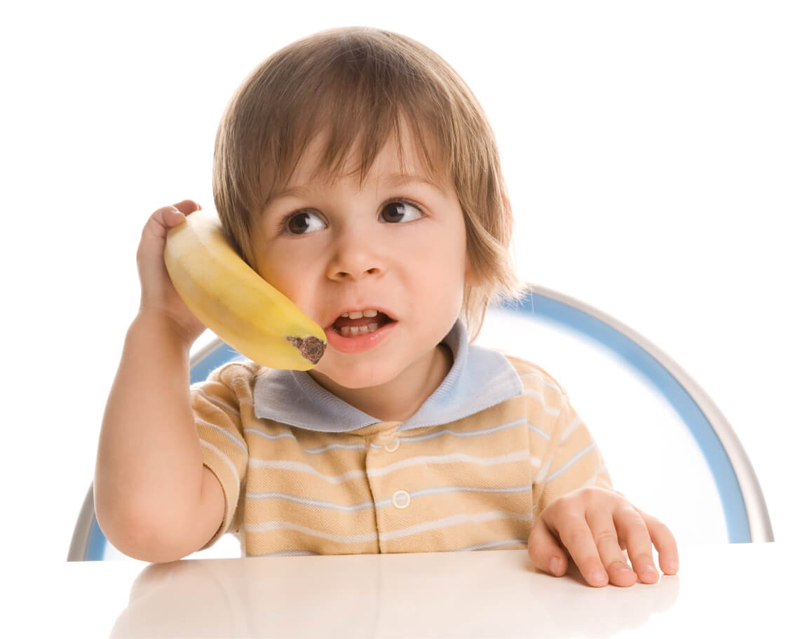 Un jeune enfant avec une banane dans les mains. 