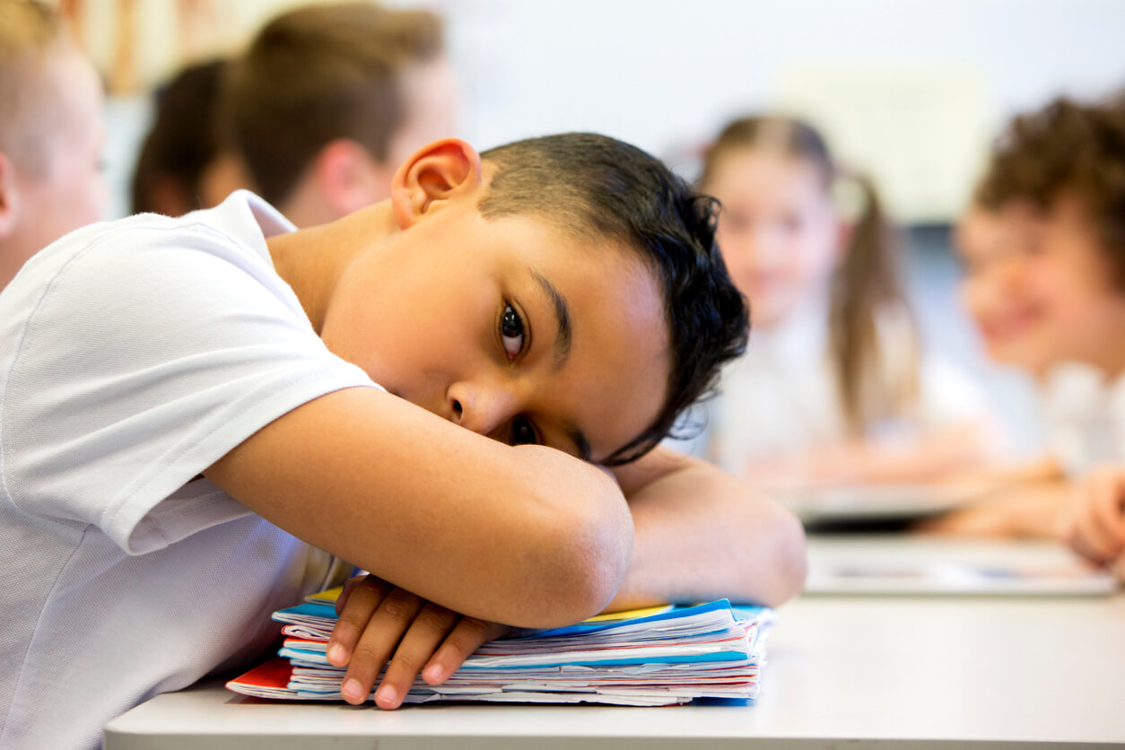 A child resting his head on his desk during class.