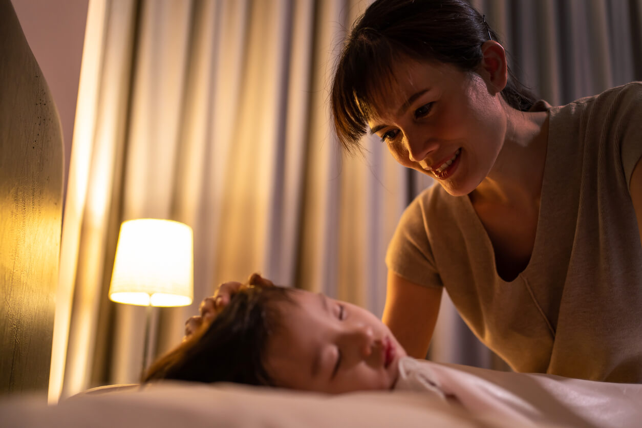 En mamma som smeker sitt sovande barns huvud.