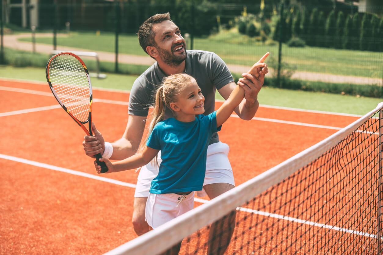 En ung jente som lærer tennis.