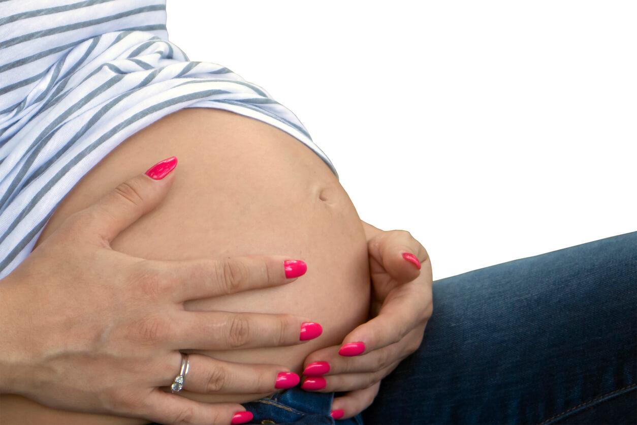 Le ventre d'une femme enceinte avec des mains manucurées.