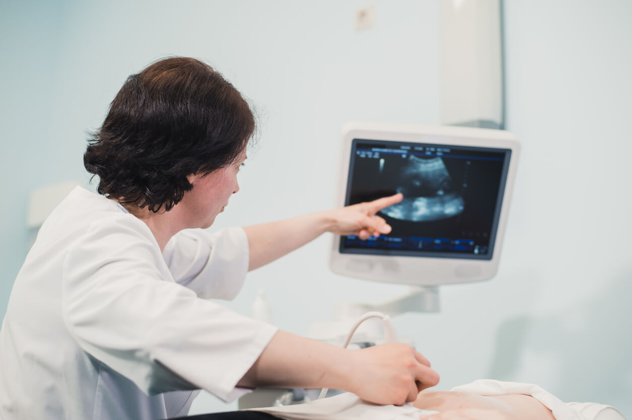 En tekniker som pekar på en skärm under ett fetalt ultraljud.