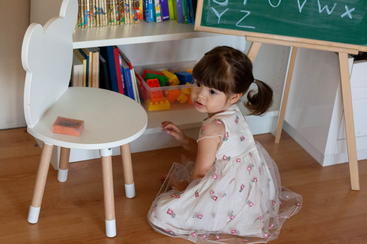 A toddler sitting on the floor in her playroom.