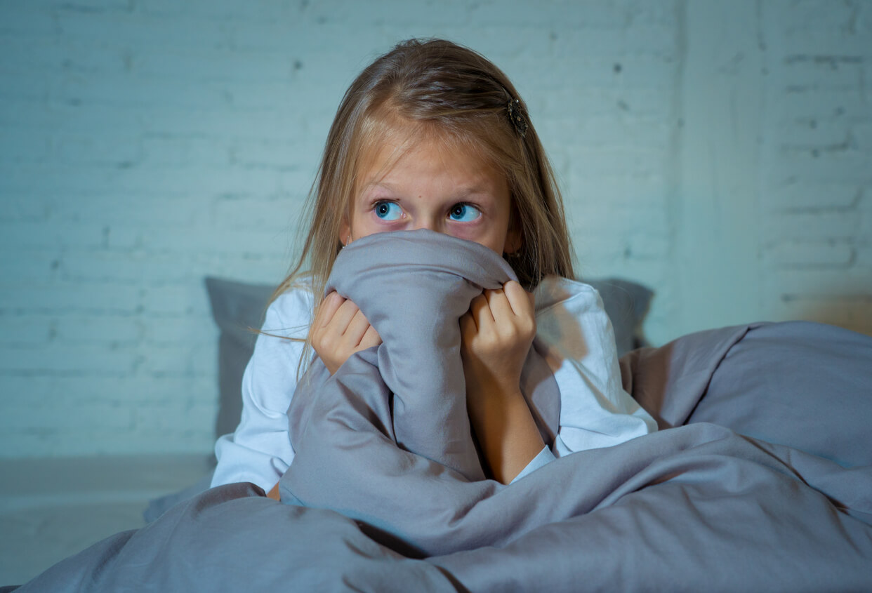 Une jeune fille qui a peur dans son lit.