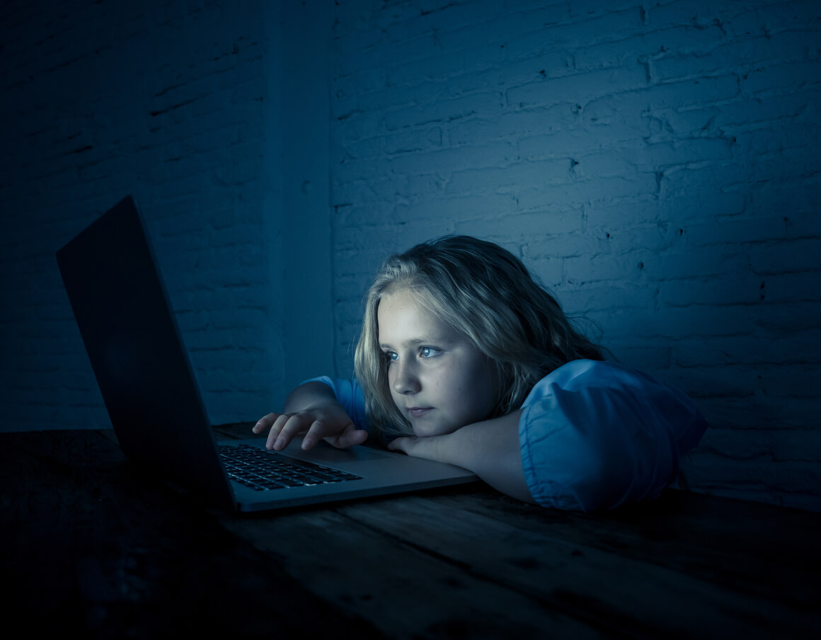Une jeune fille sur un ordinateur en pleine nuit;