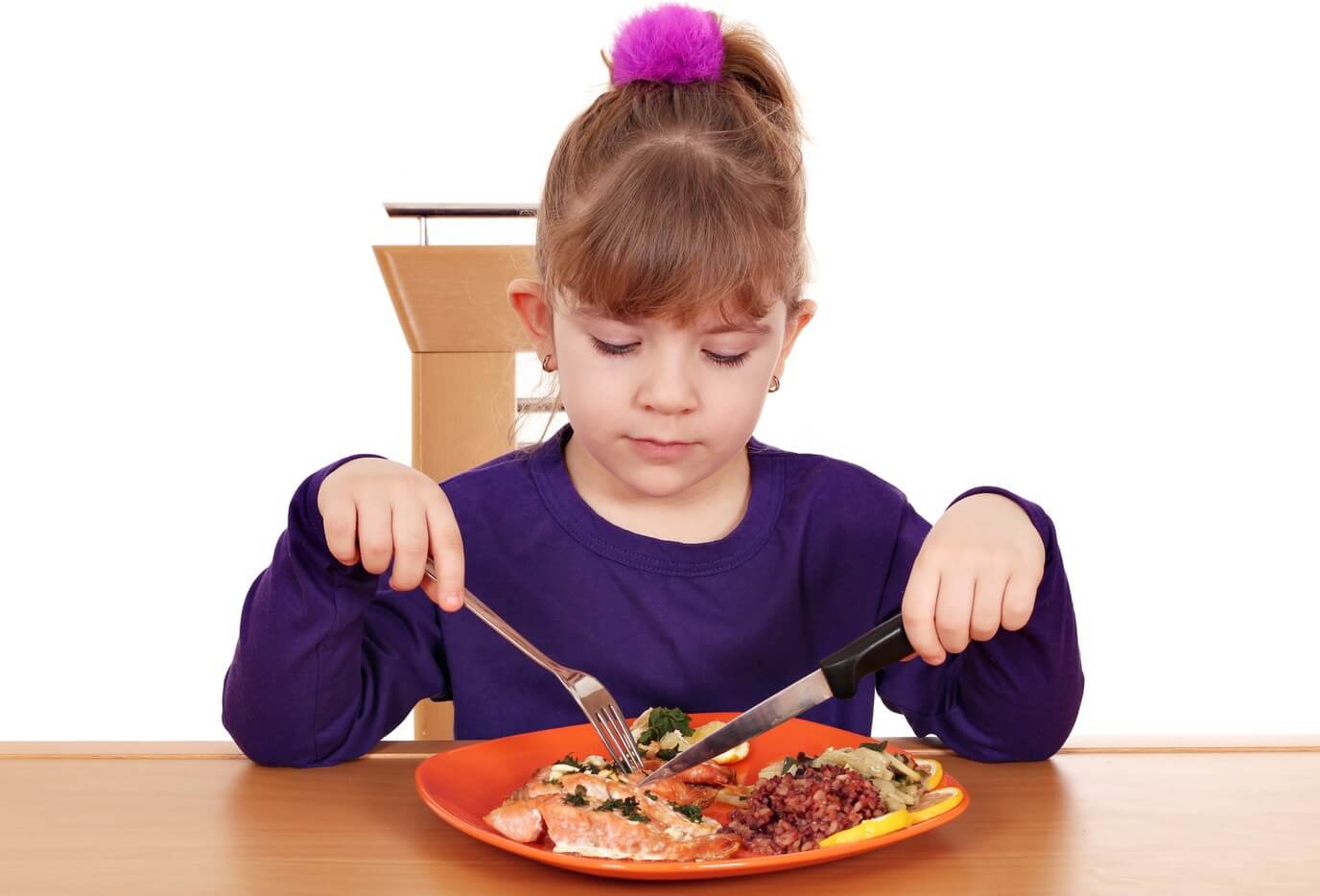 A child eating a healthy plate of salmon.