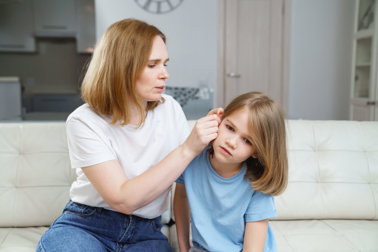 Une maman qui regarde dans l'oreille de sa fille.