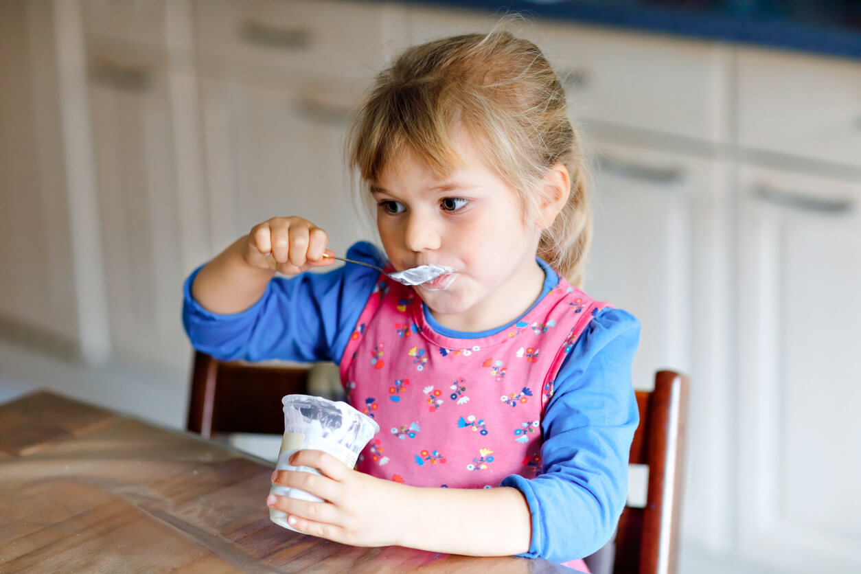 A little girl eating yogurt.