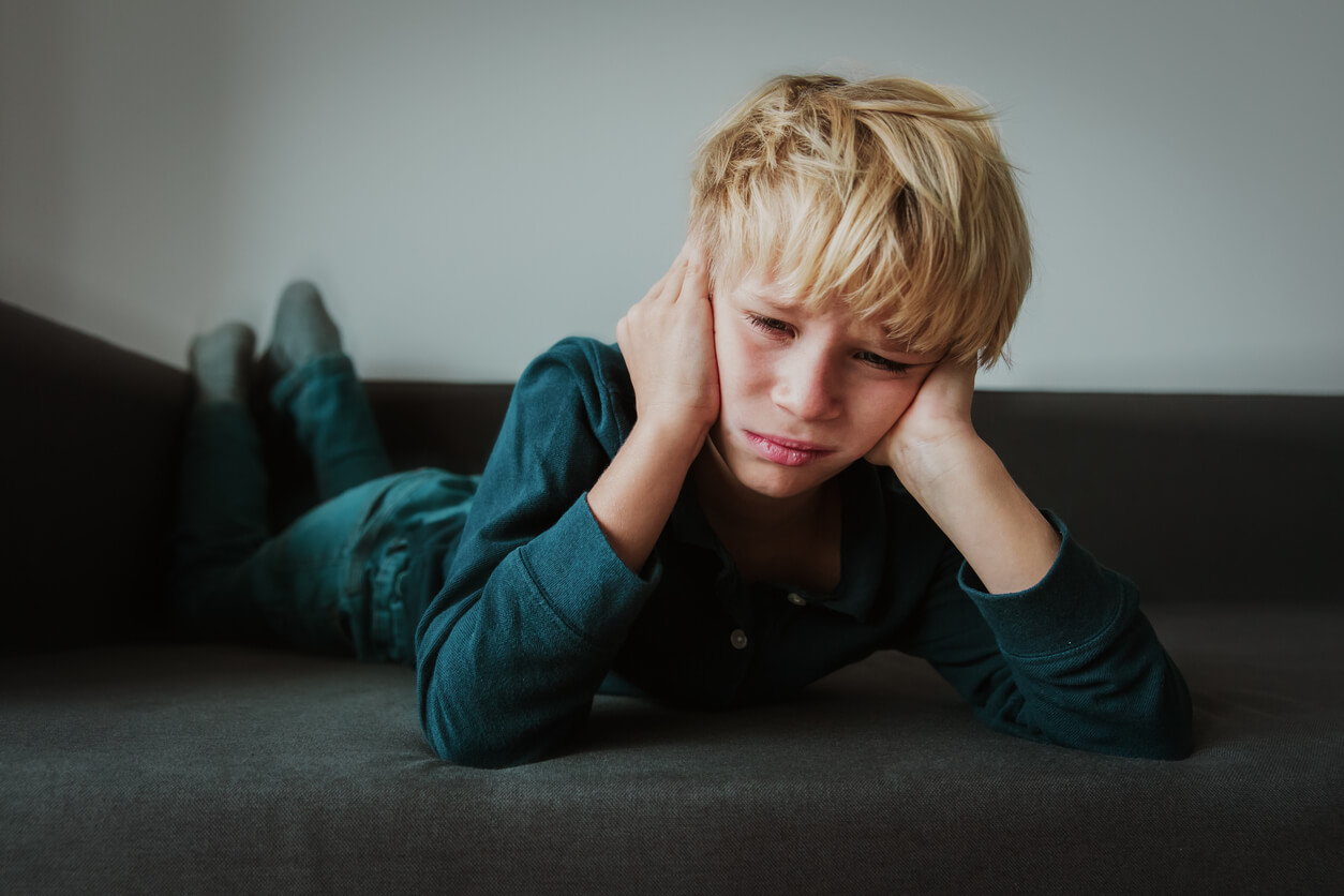 Un jeune garçon triste, allongé sur le sol.