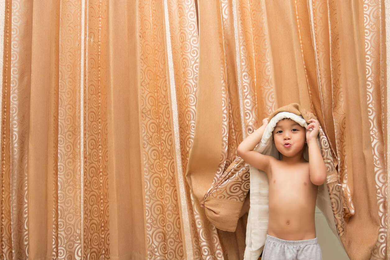 Un enfant qui joue avec des rideaux.