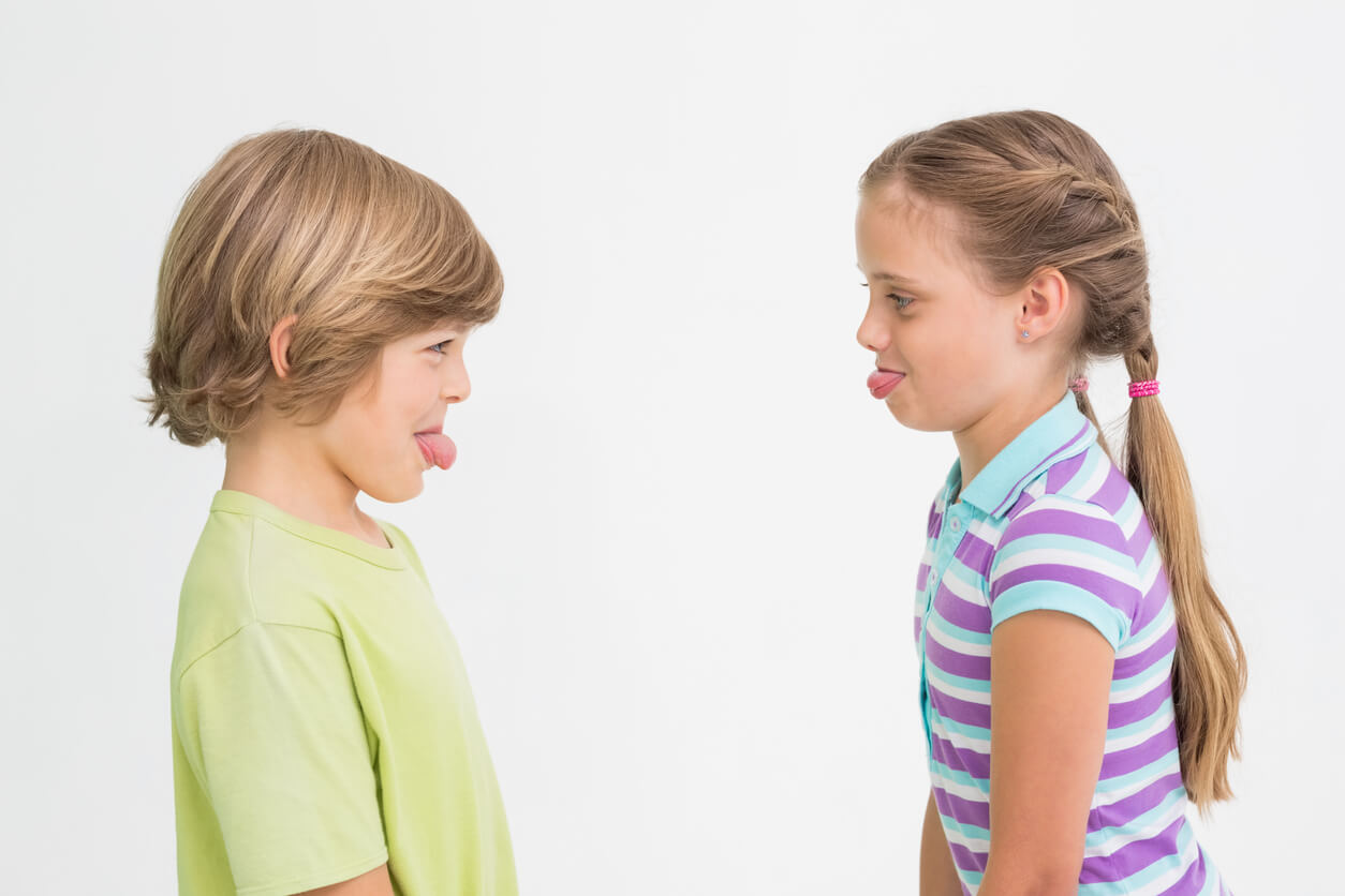Two children laughing as they stick their tongues out at one another.
