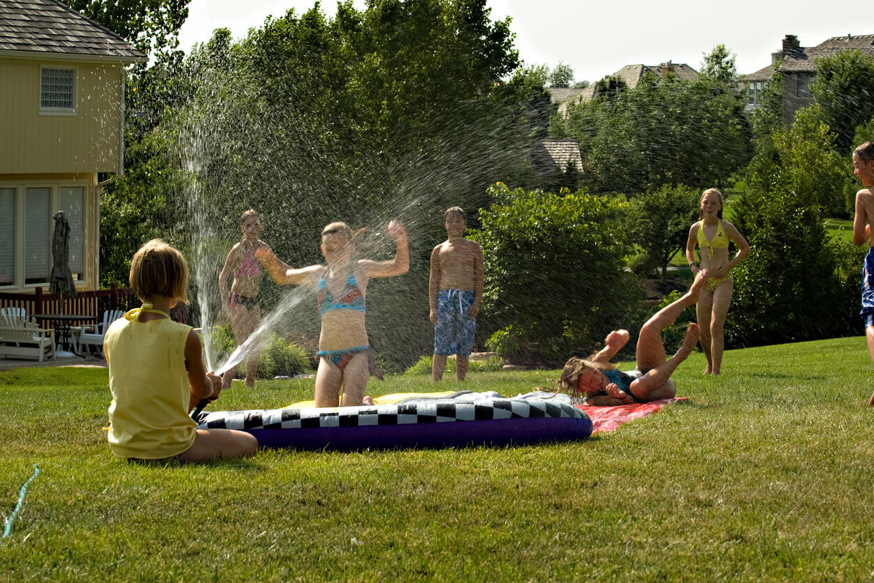 Un groupe d'enfants qui jouent dans un jardin au bord d'une piscine.