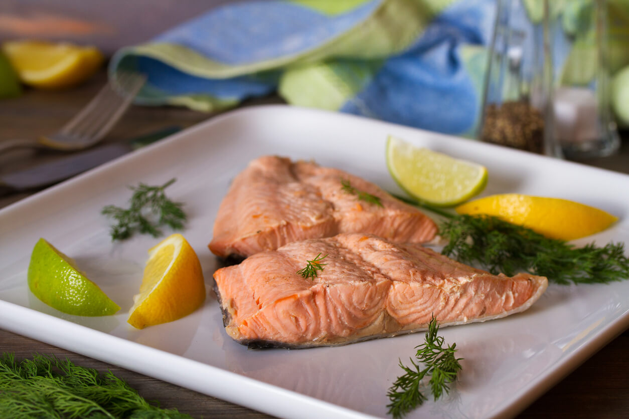 A plate of cooked salmon with citrus slices and parsley.