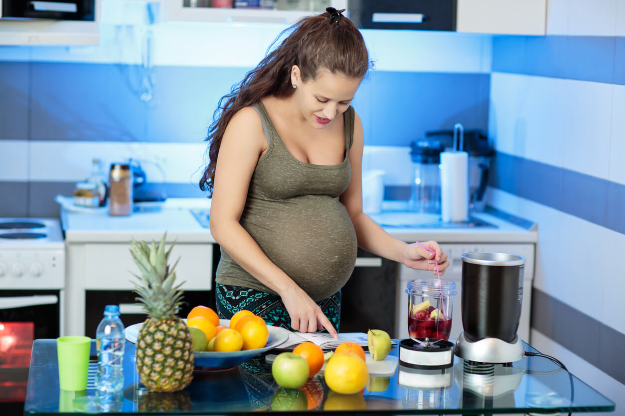 Une femme enceinte qui cuisine des fruits.