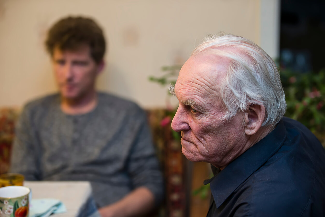 Un homme âgé à table avec un homme plus jeune.