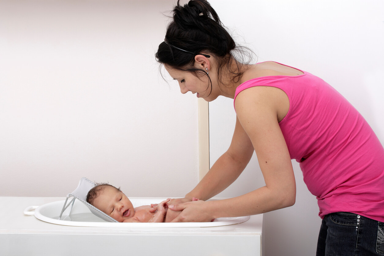 A woman bathing a newborn.