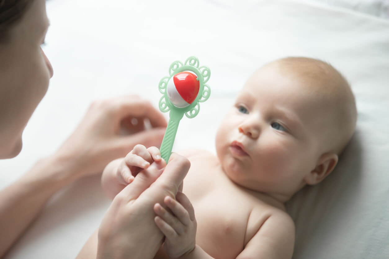 A baby looking at a rattle.
