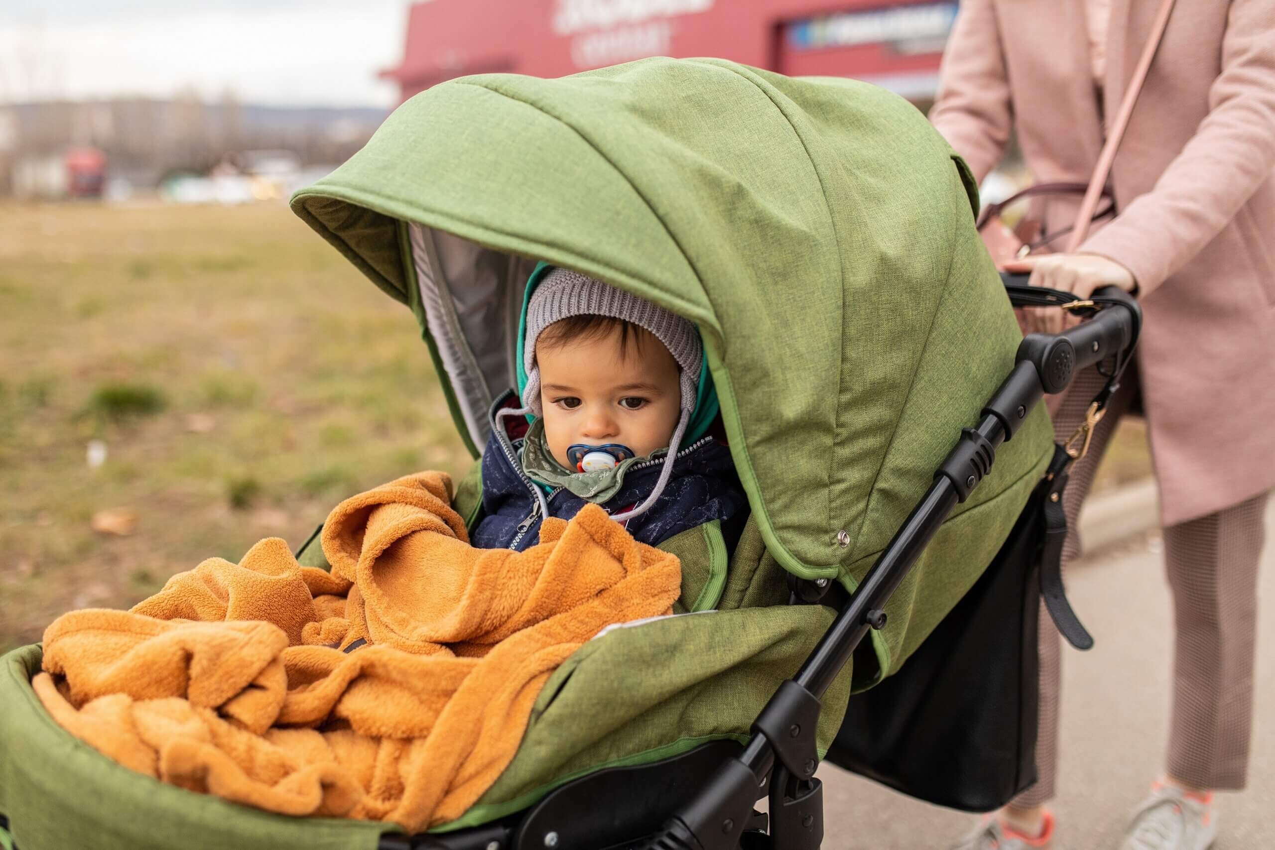 A woman taking her baby for walk in his stroller on a cold day.