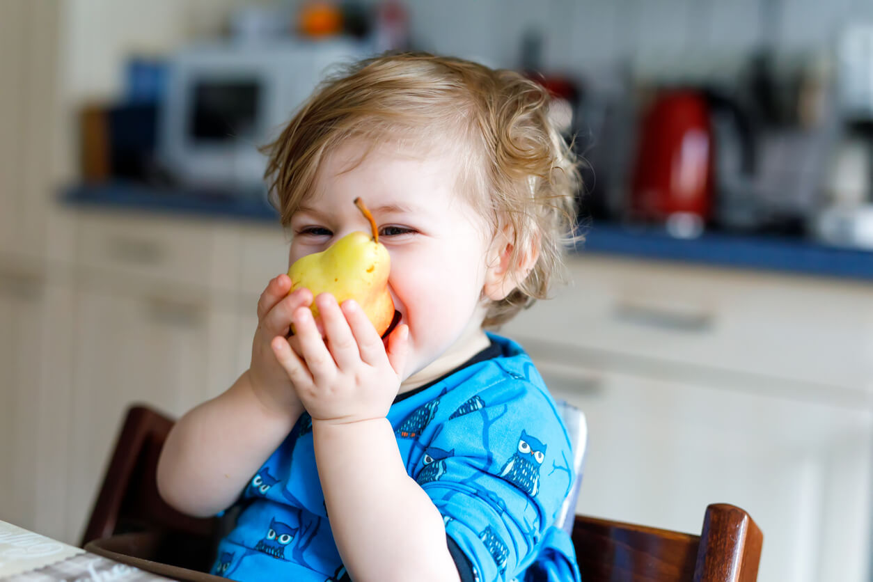 A baby biting into a pear.