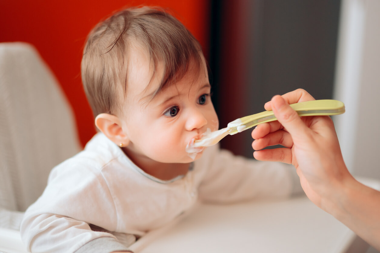 A baby eating yogurt.