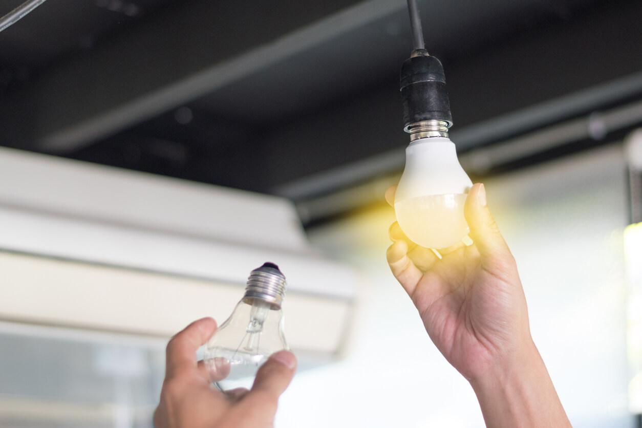 A person replacing a traditional light bulb with one that's less energy-consuming.
