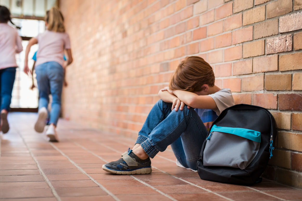 En barneskolegutt som sitter på gulvet og føler seg ubrukelig.