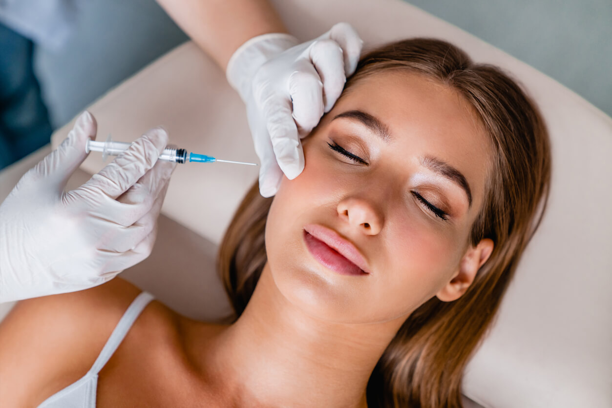 En kvinna får injektioner i ansiktet.